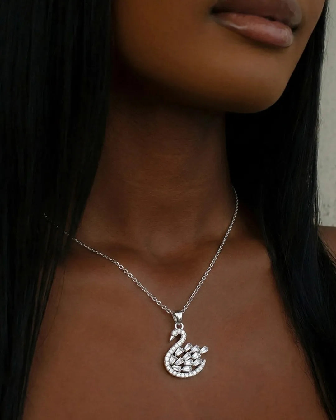Silver swan pendant necklace on a person with long dark hair.