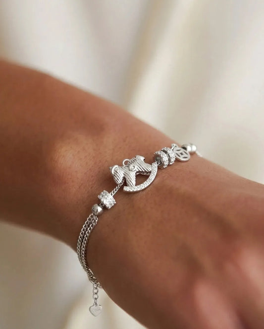 Silver bracelet with an anchor charm on a wrist against a neutral background