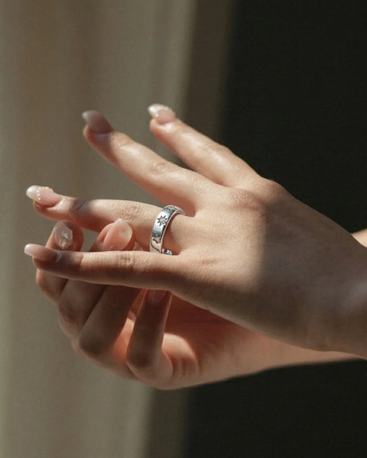 Close-up of a hand with a ring on a neutral background