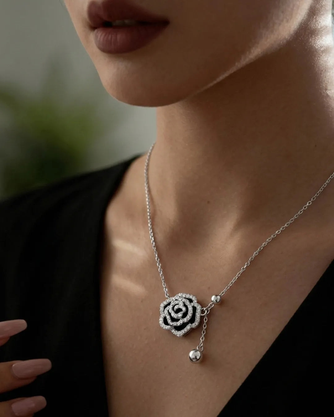 Necklace with a rose-shaped pendant worn by a person against a blurred background
