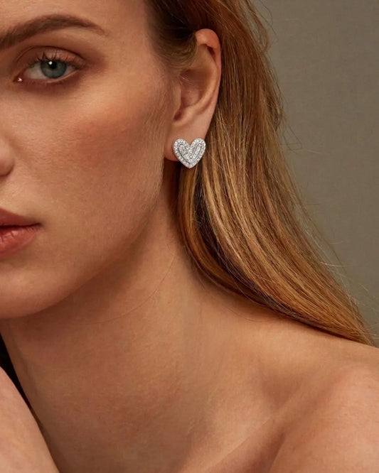 Close-up of a woman wearing a heart-shaped earring with a neutral background