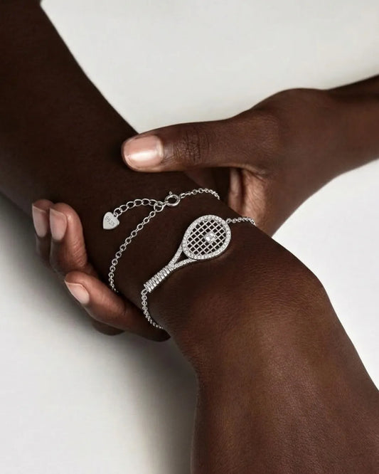 Two hands wearing silver bracelet with tennis racket design on a white background