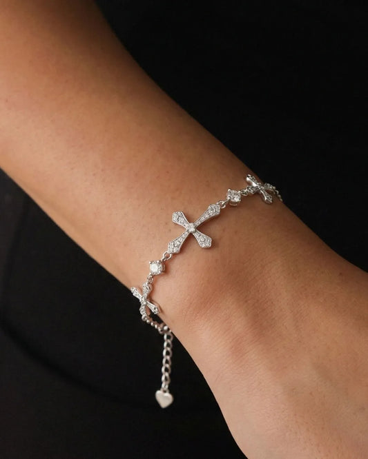 Silver bracelet with heart charm on a wrist against a black background