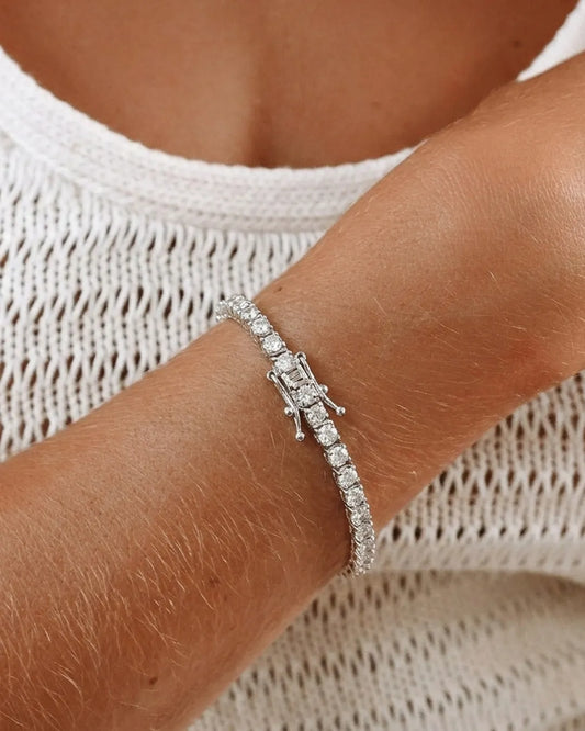Silver bracelet on a wrist with a neutral background