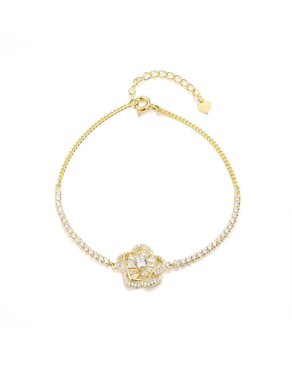 Gold bracelet with a floral clasp on a white background