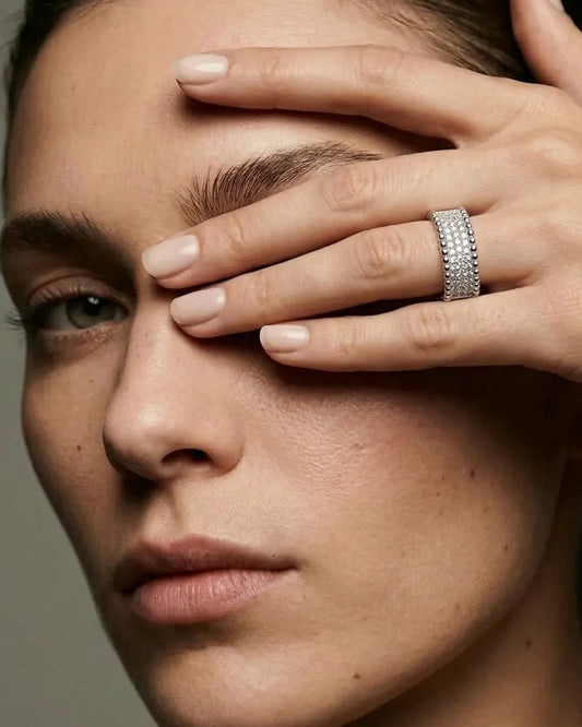 Close-up of a person with a hand covering their face, wearing a silver ring.