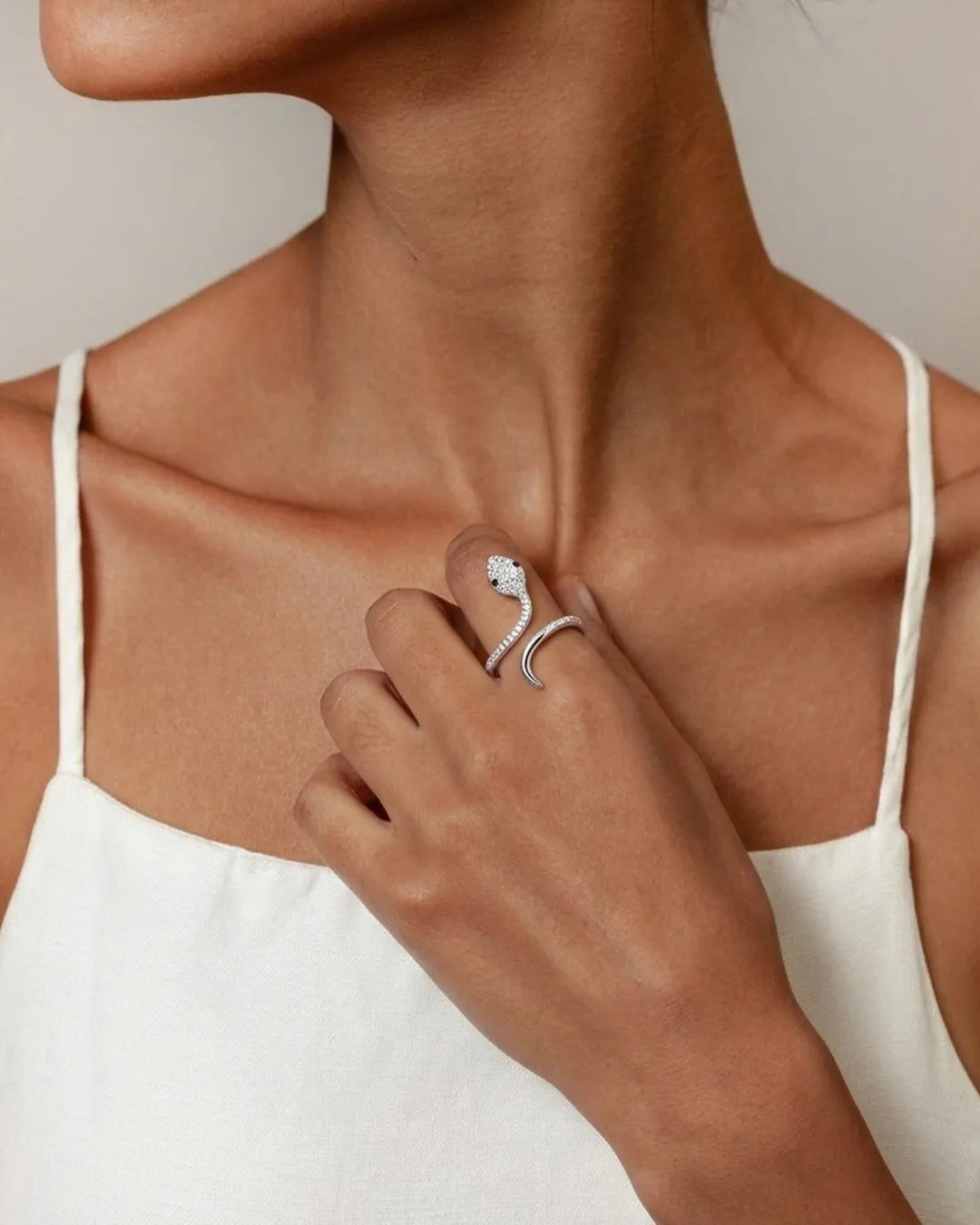 Close-up of a person wearing a silver ring with a unique design on a neutral background