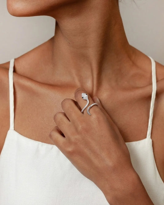 Close-up of a person wearing a silver ring with a unique design on a neutral background