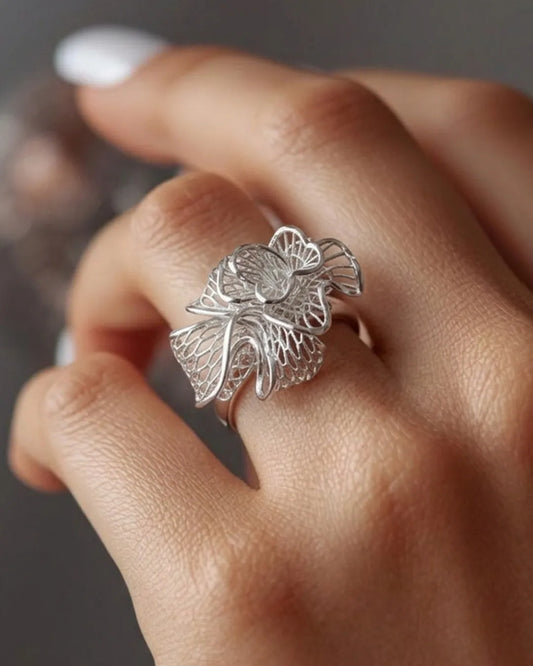 Silver leaf-shaped ring on a finger with a blurred background