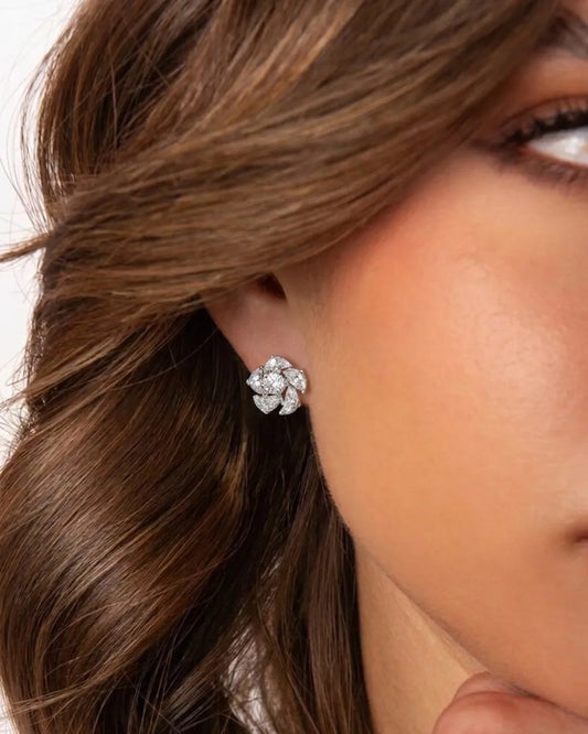 Close-up of a diamond earring worn by a person with brown hair.