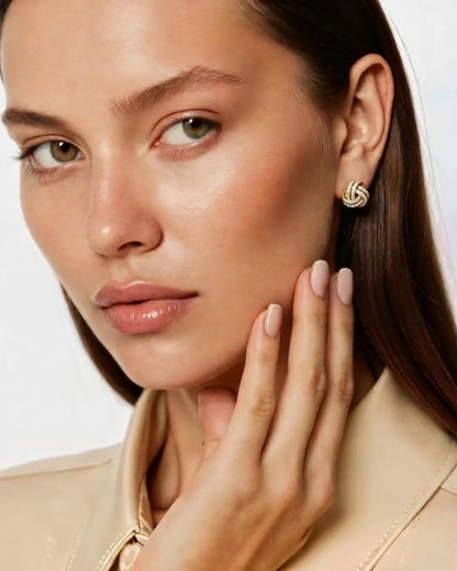 Close-up of a woman wearing gold earrings with a neutral background