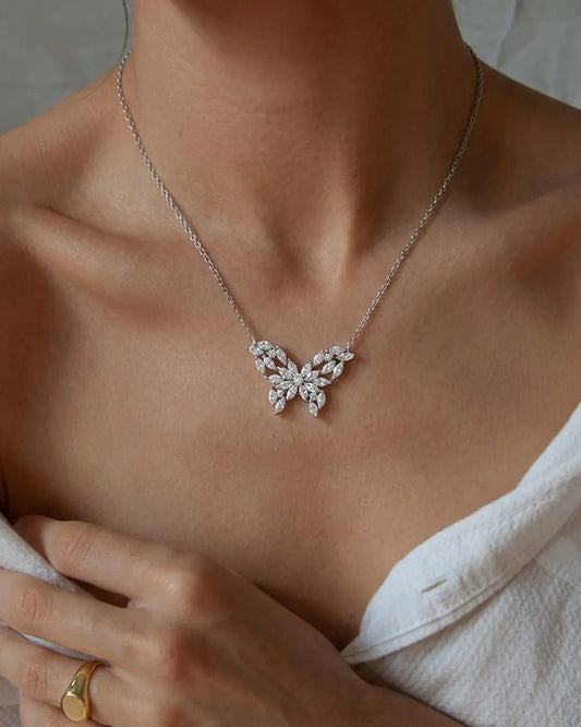 Butterfly-shaped necklace worn by a person with a neutral background