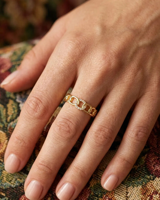 Gold chain ring on a hand with a patterned fabric background