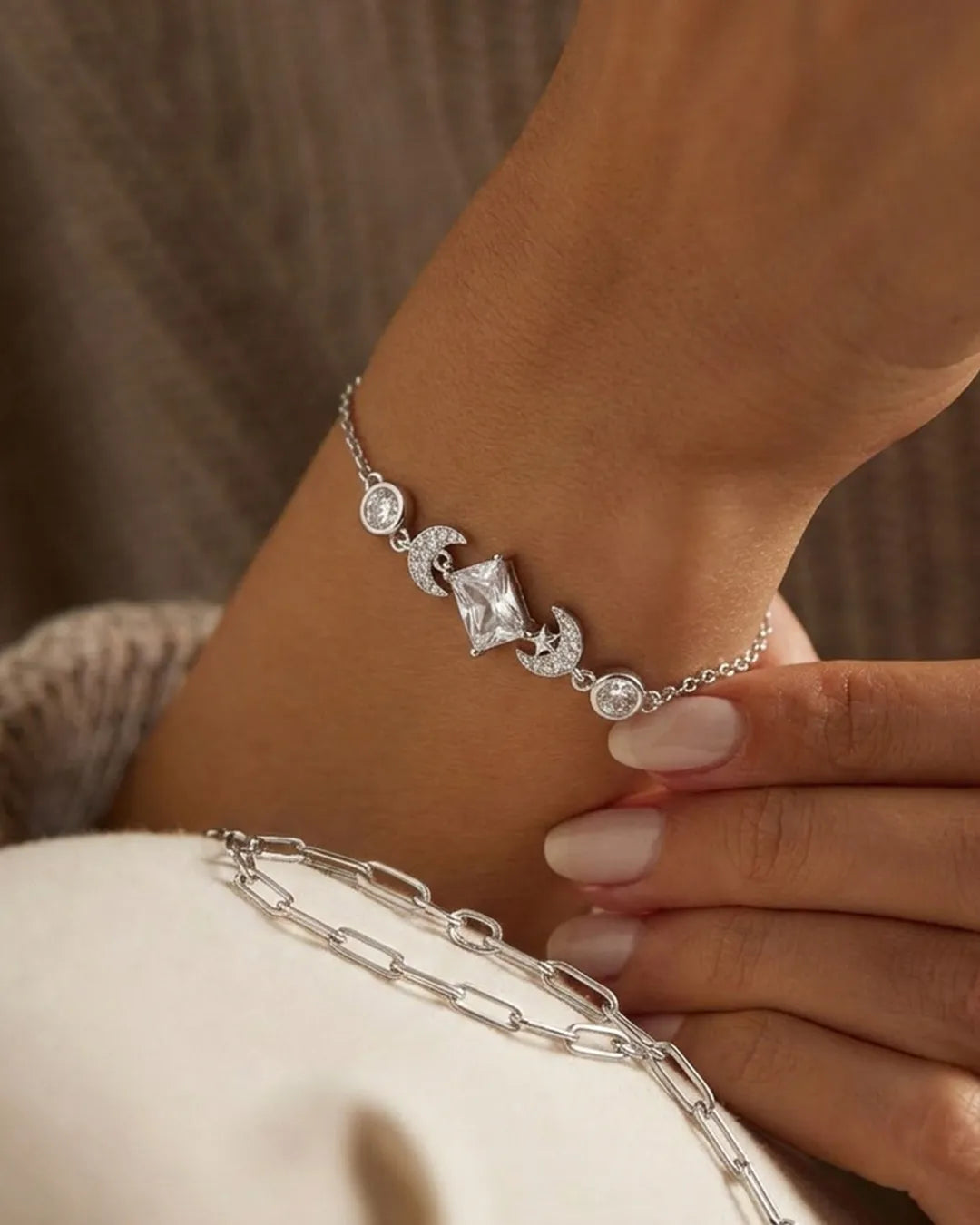 Silver bracelet with a central diamond on a wrist against a neutral background