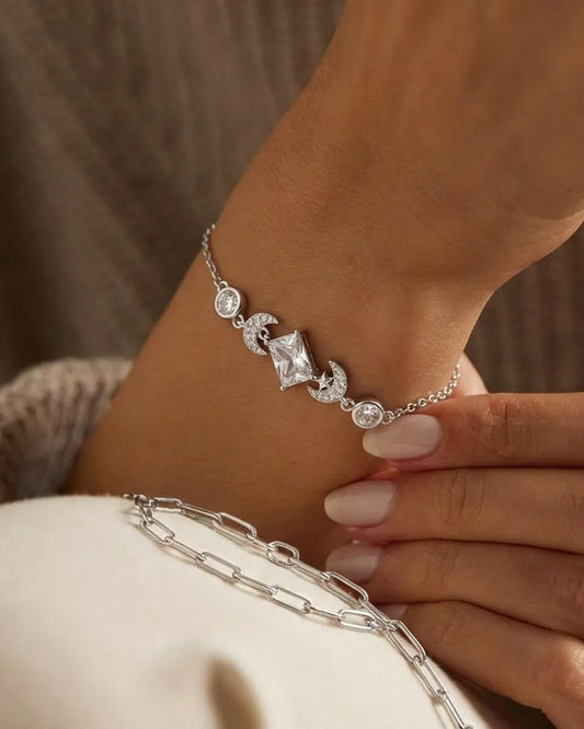 Silver bracelet with a central diamond on a wrist against a neutral background