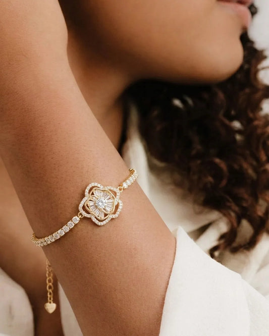 Close-up of a person's wrist wearing a gold bracelet with a diamond-like stone.