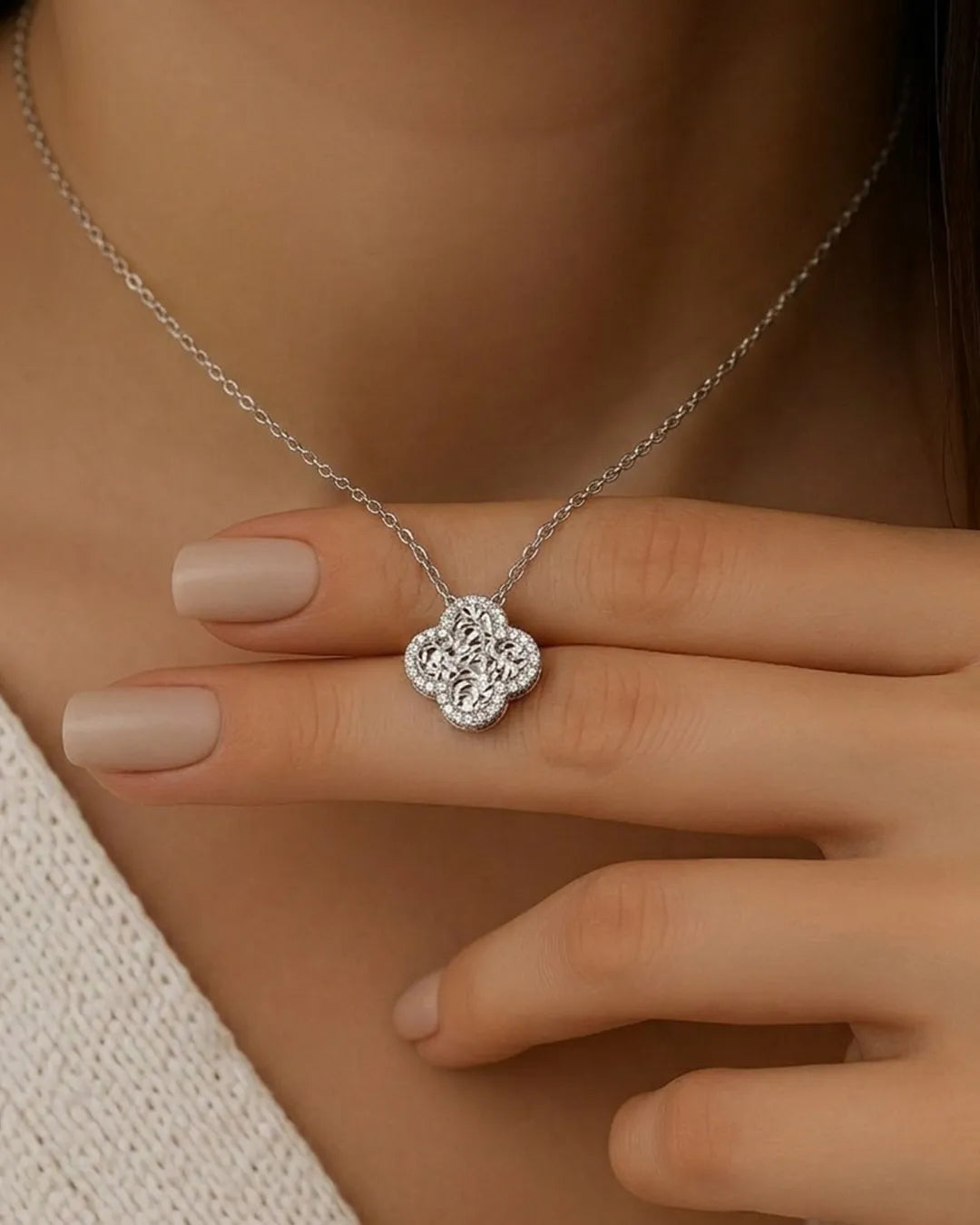 Silver necklace with a floral pendant worn by a person