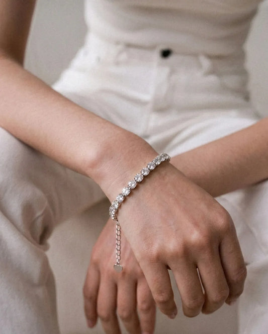 Close-up of a hand wearing a silver bracelet with a neutral background