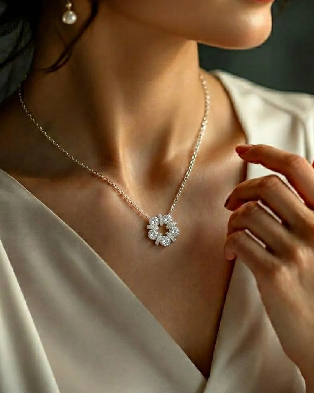 Close-up of a person wearing a delicate necklace with a floral pendant.