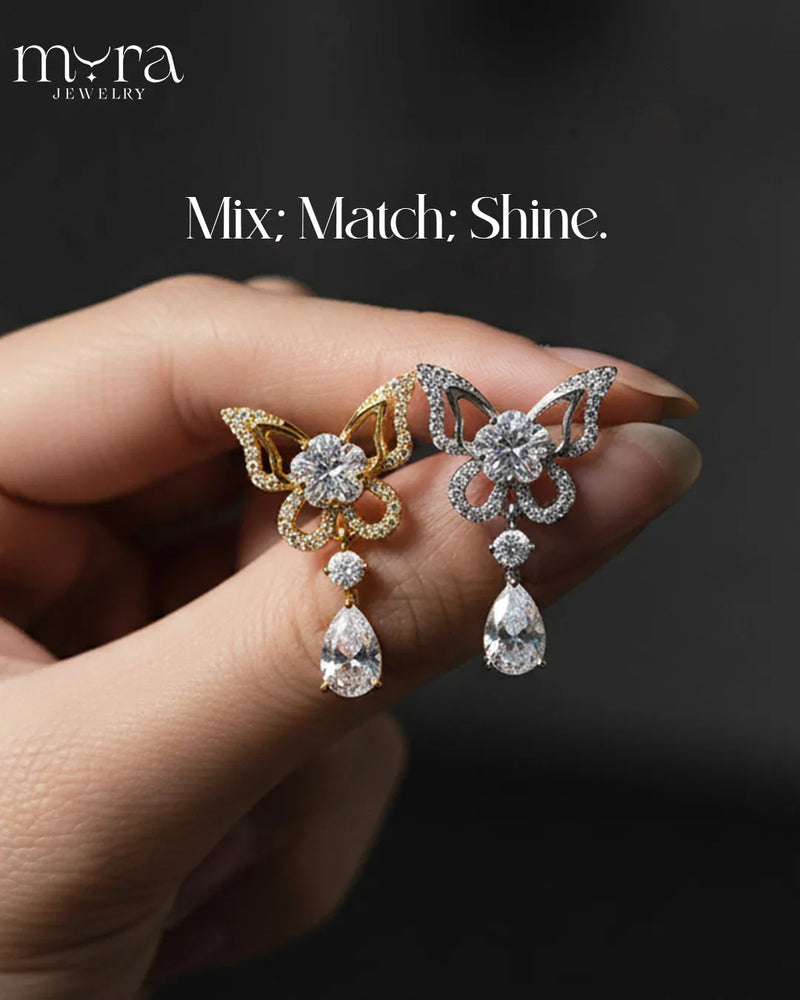Butterfly-shaped earrings with teardrop designs held by a hand, branded 'Mira Jewelry'.